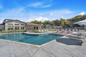una piscina con sedie e un ombrellone di Landing Apartments - Cedar Lakes a Duncanville