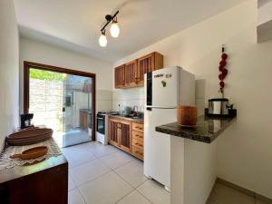 a kitchen with a white refrigerator and wooden cabinets at Casa Vila São Miguel in Itacaré