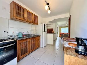 a kitchen with wooden cabinets and a white refrigerator at Casa Vila São Miguel in Itacaré +3 photos