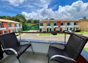 two chairs on a balcony with buildings in the background at Casa Vila São Miguel in Itacaré