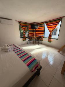 a bedroom with a bed and two chairs and windows at Hostal Casa Bohemia in Mérida