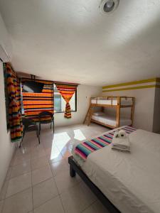 a bedroom with a bed and a desk and a chair at Hostal Casa Bohemia in Mérida