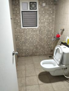 a bathroom with a toilet and a tiled wall at Elegant Stay at Bangalore International Airport in Bangalore