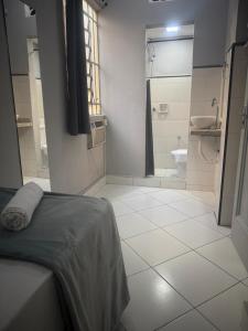 a bathroom with a bed and a shower and a toilet at Unity Hotel - Santos in Santos