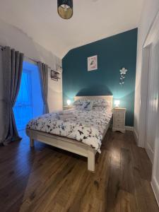 a bedroom with a bed and a blue wall at Y Beudy Bach in Kidwelly