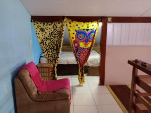 a living room with curtains and a chair and a couch at Hostel & Cia Itanhaém in Itanhaém