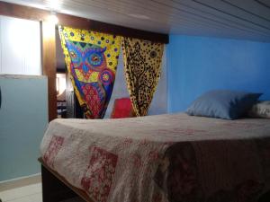 a bedroom with a bed with a colorful blanket at Hostel & Cia Itanhaém in Itanhaém