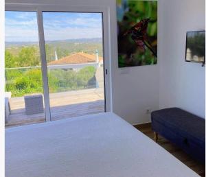 een slaapkamer met een bed en een groot raam bij Casa Bravo in Querença