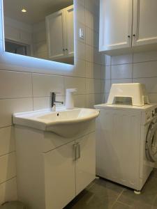 een witte badkamer met een wastafel en een wasmachine bij Sättraby villa in Norrtälje