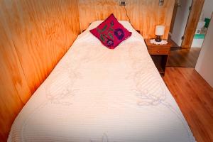 - un lit avec un oreiller rouge dans l'établissement Cabañas Altos de Ñida, à Aytuy