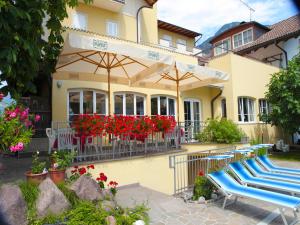 a group of chairs and umbrellas in front of a house at Hotel Stampfer B&B in Laives