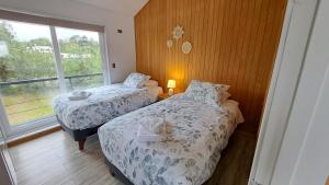 two beds in a room with a window at Casa Campo Chiloé in Chonchi