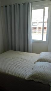 ein leeres Bett in einem Schlafzimmer mit Fenster in der Unterkunft Solaris Residencial Clube in Ilhéus + 45 Fotos