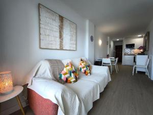 een woonkamer met een witte bank met kussens erop bij Looking at the ocean sunset in Puerto de la Madera