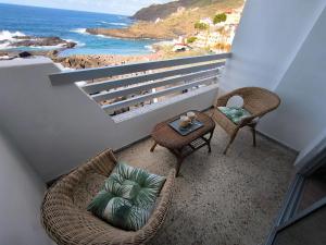 een balkon met stoelen en een tafel en de oceaan bij Looking at the ocean sunset in Puerto de la Madera