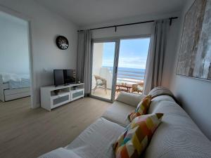 een woonkamer met een bank en uitzicht op de oceaan bij Looking at the ocean sunset in Puerto de la Madera