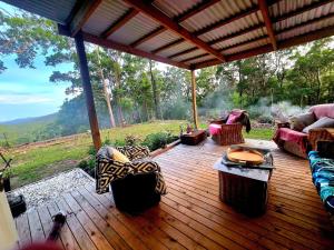 eine Veranda mit Sofas und Stühlen auf einem Holzdeck in der Unterkunft Gold Coast Hinterland Experience No ppl 8 in Tallebudgera