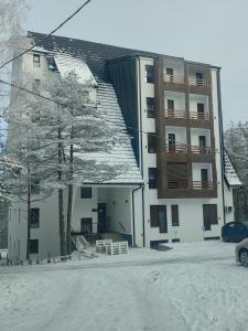 a building with snow on the ground in front of it at Vidak apartman in Divčibare