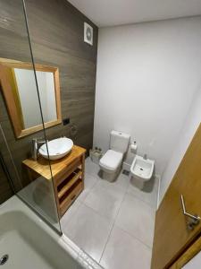 ein Badezimmer mit Waschbecken, Toilette und Spiegel in der Unterkunft Cabañas en Valeria del Mar in Carilo