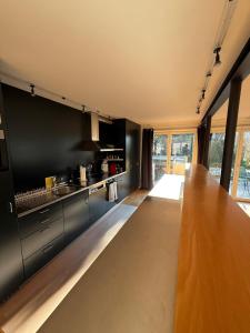 een keuken met zwarte kasten en een houten aanrechtblad bij LaVida Star Alpine Hideaway Thun, Sauna, free parking in Blumenstein