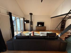 ein Wohnzimmer mit schwarzem Sofa und Fernseher in der Unterkunft LaVida Star Alpine Hideaway Thun, Sauna, free parking in Blumenstein