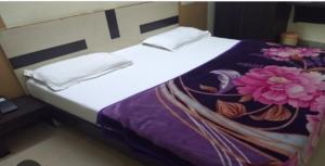 a bed with white sheets and pink flowers on it at Chaudhary dharamshala in Jāmb +5 photos