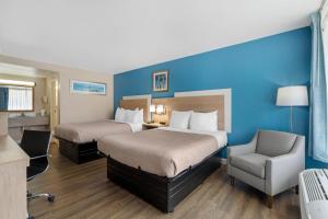 ein Hotelzimmer mit zwei Betten und einem Stuhl in der Unterkunft Quality Inn & Suites Conference Center in New Port Richey