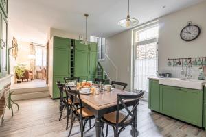 a kitchen with green cabinets and a table with chairs at La Grive - Petit nid douillet proche de la plage in Étretat