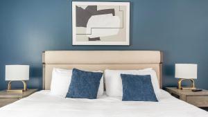 a bedroom with blue walls and a bed with two lamps at Landing Apartments - The Carlisle at Dunedin in Dunedin