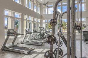 una palestra con una fila di tapis roulant ed ellittiche di Landing Chic 1BD Pool Gym a Black Horse Run