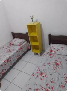 une chambre avec deux lits et une commode jaune dans l'établissement Casa espaçosa, à Garanhuns