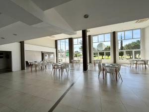 una grande stanza con sedie, tavoli e finestre di Rincón del Sol - Suite 09 a Pinamar