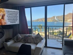een woonkamer met een bank en uitzicht op de oceaan bij Alojamiento Peñón del rodadero in Santa Marta +59 foto's