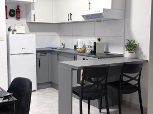 a kitchen with white cabinets and black chairs at D' Suites Holiday Apartments in Il-Gżira