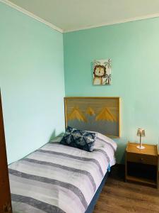 a bedroom with a bed with a blue wall at Casa Lepeley Colimilla in Frutillar +4 photos