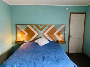 a bedroom with a blue bed with two lamps at Casa Lepeley Colimilla in Frutillar