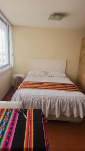 een slaapkamer met een groot bed en een gestreepte deken bij Plaza murillo in La Paz