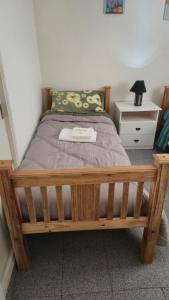 ein Bett in einem Schlafzimmer mit einem Holzrahmen und einem Nachttisch in der Unterkunft Valle del Río Chico in Gobernador Gregores