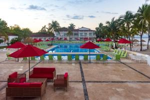 una piscina con mesas, sillas y sombrillas rojas en Royal Decameron Indigo - All Inclusive, en Montrouis