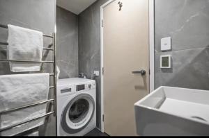 a bathroom with a washing machine and a sink at Modern Luxury Condo Shotover Views in Queenstown