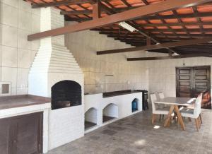 a brick oven in a room with a table and chairs at Casinha Guest House in Saquarema