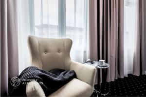 a blanket sitting in a chair in front of a window at SERENITY Aparthotels - Old Town Poznan by Friendly Apartments in Poznań