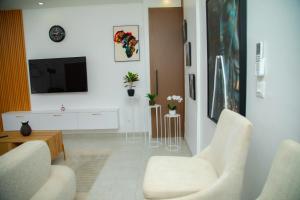 un soggiorno con due sedie e una TV a schermo piatto di Appartement Neuf meublé de Haut Standing a Dakar Altre 9 foto