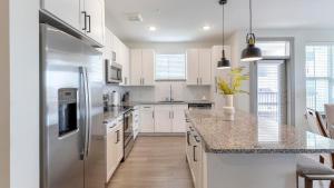 a kitchen with white cabinets and a stainless steel refrigerator at Landing Apartments - Atlas Bluewood in Celina