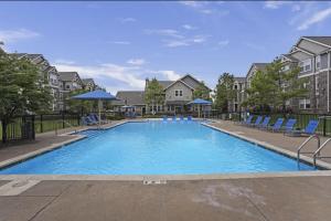 een groot zwembad met blauwe stoelen en gebouwen bij Landing Stylish 1BD Courtyard Pool in Broken Arrow