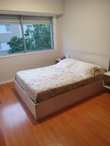 een bed in een slaapkamer met een groot raam bij Departamento en Barrio La Perla, Mdp in Mar del Plata