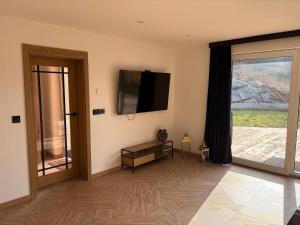 un soggiorno con televisione e porta scorrevole in vetro di Apartamenty Słowianka-Chatka pod lasem a Wolibórz