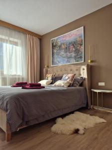 ein Schlafzimmer mit einem großen Bett mit einem Gemälde an der Wand in der Unterkunft OTILIA apartment in Zell am See