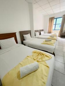 a row of four beds in a room at Hotel Las Peñas in Guayaquil