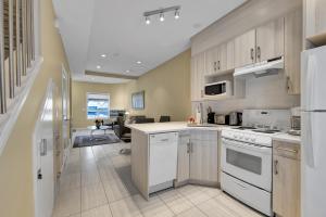 a kitchen with white appliances and a living room at banff woods lodge in Canmore